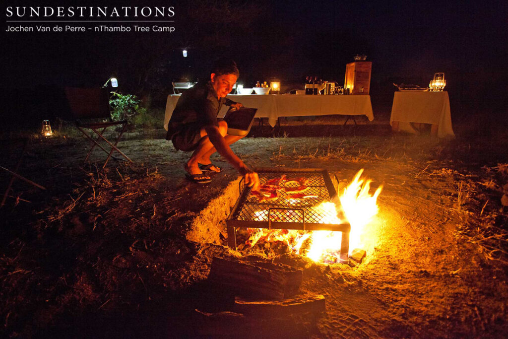 Hennie stacking the coals and arranging the meat on the braai Hennie stacking the coals and arranging the meat on the braai