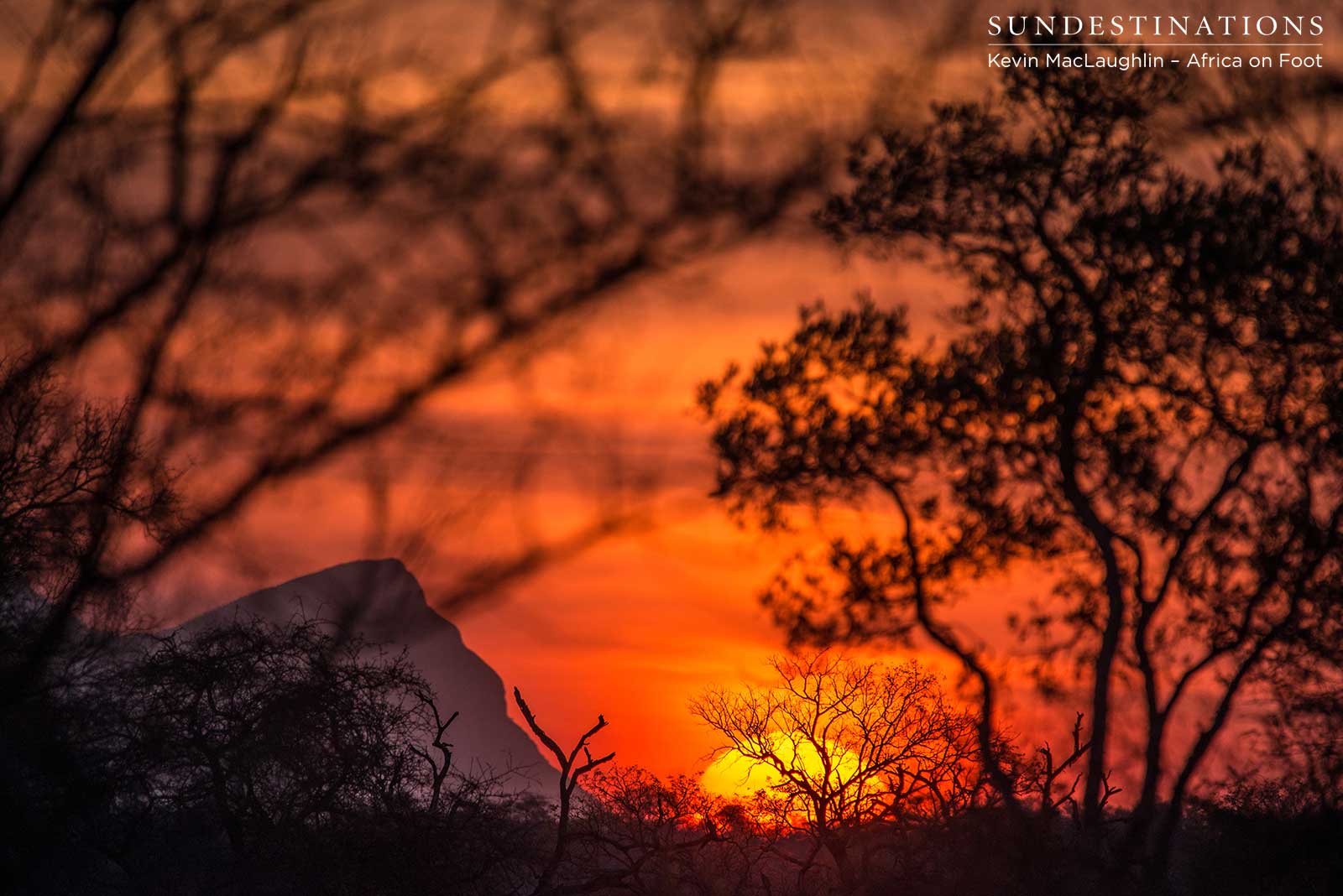 A peak of the Drakensberg Mountains peeks over the horizon as the setting sun bathes the sky in bright colours of summer A peak of the Drakensberg Mountains peeks over the horizon as the setting sun bathes the sky in bright colours of summer